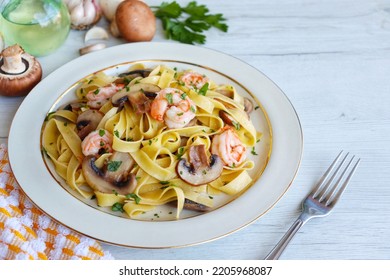 Italian Traditional Dish"Tagliatelle con Funghi e Gamberi",tagliatelle pasta with mushrooms,prawns,olive oil,garlics,parleys,salt and peppers on plate with white wood background.Copy space

 - Shutterstock ID 2205968087