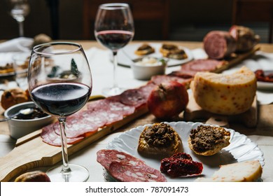Italian Tuscan wooden table full of typical dishes, salami, cheese, vegetables and red chianti wine in a Classy and stylish environment 