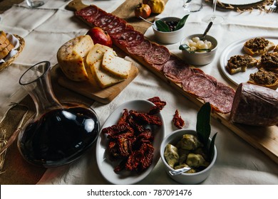 Italian Tuscan wooden table full of typical dishes, salami, cheese, vegetables and red chianti wine in a Classy and stylish environment 