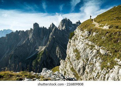Italy, Dolomites - Man hiker standing very far from the edge of the barren rocks 
