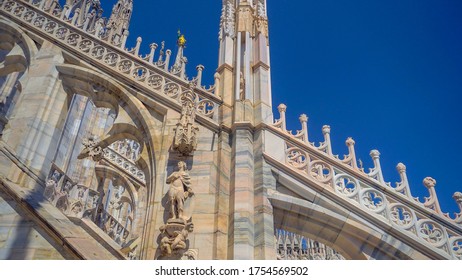 Italy, Milan, June 12, 2020: roof. The Duomo di Milano Cathedral in front of the Victor Emmanuel II Gallery in Piazza. View of krishy houses. Architetture Statues on the spiers of the building. Gothic