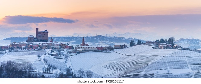 Italy Piedmont: panoramic winter snow view wine yards unique landscape at sunset, Serralunga d'Alba medieval castle and villages on hill top, the Alps in the background dramatic sky