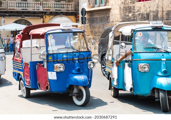 ITALY, SICILY, PALERMO - 30 JULY 2021: Ape Tuk\
Tuks next to The Cathedral of Palermo. Three-wheel taxis on the\
streets of Palermo. Extraordinary vehicle for city tours in\
Palermo, Sicily, Italy.