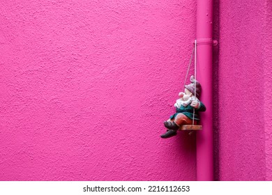 Italy, Venice, Burano Island. Hot Pink Wall With A Gnome Hanging In The Corner On Burano Island.