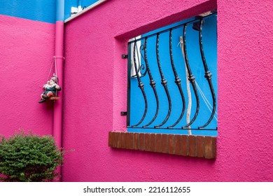 Italy, Venice, Burano Island. Hot Pink Wall With A Gnome Hanging In The Corner On Burano Island.