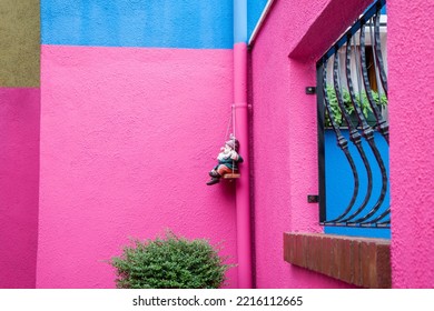 Italy, Venice, Burano Island. Hot Pink Wall With A Gnome Hanging In The Corner On Burano Island.