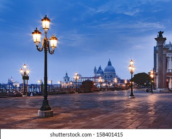 Italy Venice sunrise view on st marco square and Sana Maria Della Salute cathedral between illuminated street lamps - Powered by Shutterstock