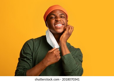 Itchy Skin. Irritated Young Black Guy Scratching Face After Wearing Protective Medical Mask, Annoyed African American Man Having Allergy, Standing Isolated Over Yellow Background, Copy Space