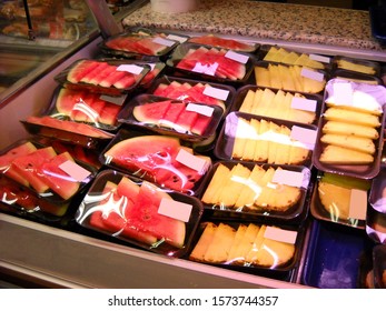 Items On Display In A Store Window. Portioned Packages By Weight Of Fruit. Pieces Of Watermelon And Pineapple, Packaged In Plastic Packaging - Containers, And Wrapped In Sticky Cling Film.