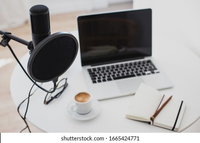 Items For Recording Podcast: Professional Microphone, Earphones And Laptop On White Table In Cozy Home Studio.