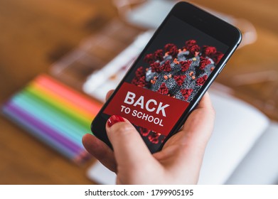 Items for the school, phone with COVID-19 warning and protective mask on dark wooden table. School supplies on dark board background during pandemic COVID-19. Back to school during pandemic. - Shutterstock ID 1799905195