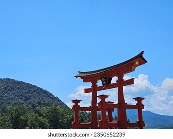 Itsukushima Shrine (厳島神社) with blue sky and green hill in background