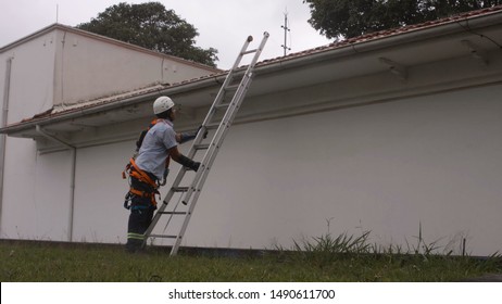 Itu, BRAZIL - 23 March 2016: Technician Climbing Portable Ladder To Do Water Box Maintenance On School Roof