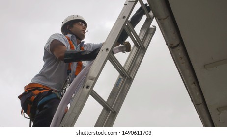 Itu, BRAZIL - 23 March 2016: Technician Climbing Portable Ladder To Do Water Box Maintenance On School Roof