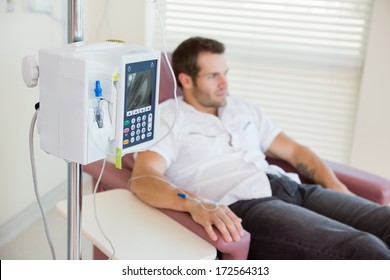 IV Drip Attached To Young Male Patient's Hand During Chemotherapy In Hospital Room