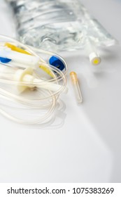 IV Drip Chamber, Tubing, And Bag Of Solution On A White Table In A Hospital.