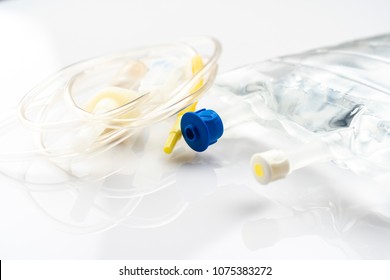 IV Drip Chamber, Tubing, And Bag Of Solution On A White Table In A Hospital.