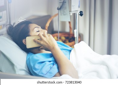 IV Drip Chamber, Tubing, And Bag Of Solution Against Blur Asian Patient Girl Resting On Hospital Bed With Mother Tack Good Care. Overload Overtime Working Blue Vintage Tone With Copay Space.