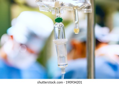 IV drip in operation room with two surgeons on background - Powered by Shutterstock