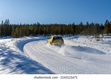 IVALO, FINLAND - February 28, 2022: Bright yellow Volkswagen Golf drives fast on a snow road during sunny day in polar Finland.