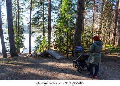 Ivande, Latvia - March 12, 2022: Woman With A Pram And Wooden Stairs In Forest. Sunny Spring Day.