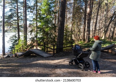 Ivande, Latvia - March 12, 2022: Woman With A Pram And Wooden Stairs In Forest. Sunny Spring Day.