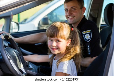 Ivano-Frankivsk, Ukraine- June 25, 2019: Happy Smiling Child Girl And Young Male Cop Inside Police Patrol Car.