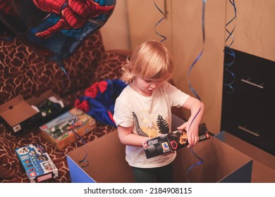 Ivanovo, Russia- January 26, 2022: Cute Caucasian  Blonde Five Years Boy Child Opening Birthday Gift Present Box In His Room Home. 