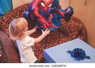 Ivanovo, Russia- January 26, 2022: Cute Caucasian  Blonde Five Years Boy Child Opening Birthday Gift Present Box In His Room Home. 