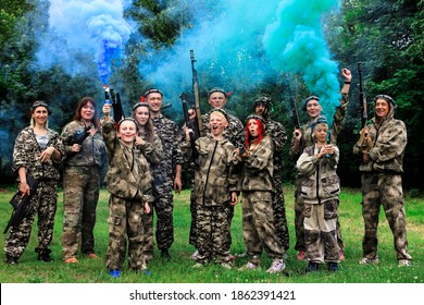 Ivanovo, Russia - July 18 2020: People in camouflage celebrating winning laser tag shooting game in open air with colored smoke.