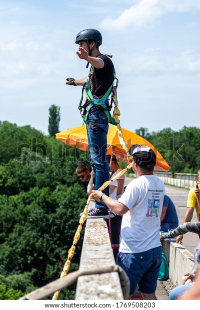 Ivanovsky Bridge,\
Ukraine - June 21, 2020: Concept of Extreme Sports and Fun. An\
instructor helps a man  to jump with a rope  from the bridge. All\
equipment is very firmly\
fixed