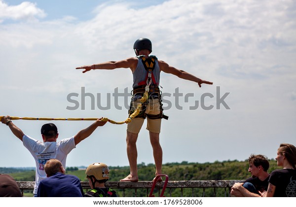 Ivanovsky\
Bridge, Ukraine - June 21, 2020: Concept of Extreme Sports and Fun.\
An instructor helps a man  to jump with a rope  from the bridge.\
All equipment is very firmly fixed and safe\
