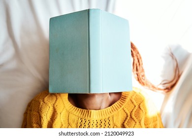 Ive Always Got My Head Stuck In The Books. Shot Of An Unrecognizable Woman Lying With A Book Over Her Face.