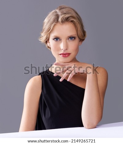 Ive been waiting for you..... A gorgeous young woman in an evening gown while isolated on a grey background.