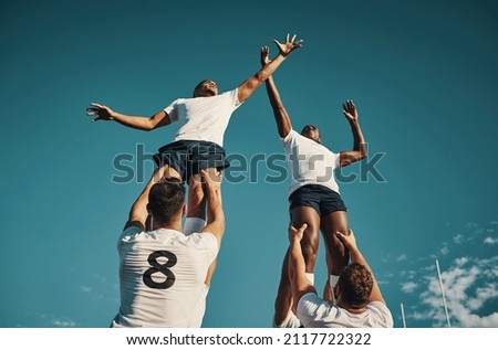 I've got it. Low angle shot of two handsome young rugby players catching the ball during a lineout on the field.
