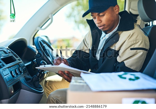 Ive got just a\
few more stops to make. Shot of a courier writing on a clipboard\
while sitting in a delivery\
van.
