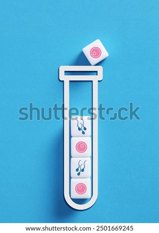 Ivf in vitro fertilization process being symbolized by sperm and egg icons on cubes falling into a test tube on blue background.