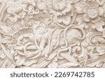 Ivory color carving of flowers and monkey in concrete on wall in Bali, Indonesia