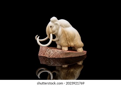 ivory statuette of elephant mammoth on black background with reflection. carved with a gouge from old bone. authentic decorative figure for interior.