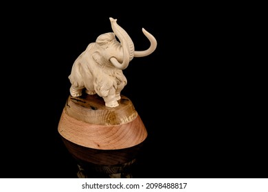 Ivory statuette of elephant mammoth on black background with reflection. carved with a gouge from old bone. authentic decorative figure for interior.