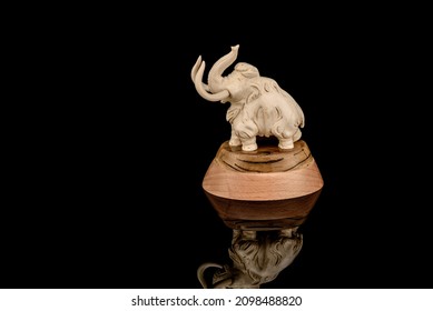 Ivory statuette of elephant mammoth on black background with reflection. carved with a gouge from old bone. authentic decorative figure for interior.