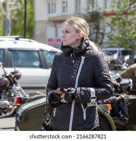 Izhevsk, Russia - May 21, 2022: Street Portrait Of A Young Fair-haired Woman Biker In A Black Biker Jacket And Gloves