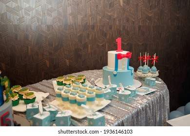 Izmail, Ukraine - May 2020. Festive candy bar for one year old boy birthday party. Cake with red number 1 butterfly bow on shirt. Blue cakepops, cupcakes with red bows and Teenage Mutant Ninja Turtles