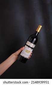Izmail, Ukraine. November 2022. Hand holding bottle of red wine Pinot Noir on black background. Bessarabia winery