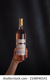 Izmail, Ukraine. November 2022. Hand holding bottle of pink wine Pinot Noir on black background. Bessarabia winery