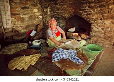 IZMIR PROVINCE, TURKEY - AUG 2: Elderly Woman Cooking Traditional Gozleme Dish In Rustic Stone Oven Of Old Turkish Village On August 2, 2015. Population Of Izmir Province Is 3.950.000 People