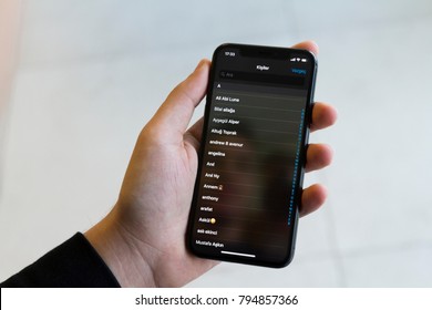 IZMIR ,TURKEY - JANUARY 14, 2018: Smartphone Apple Iphone 10 X Space Silver Grey Color. Young Man with hand Open apps social networking service CONTACTS application at screen on white background.