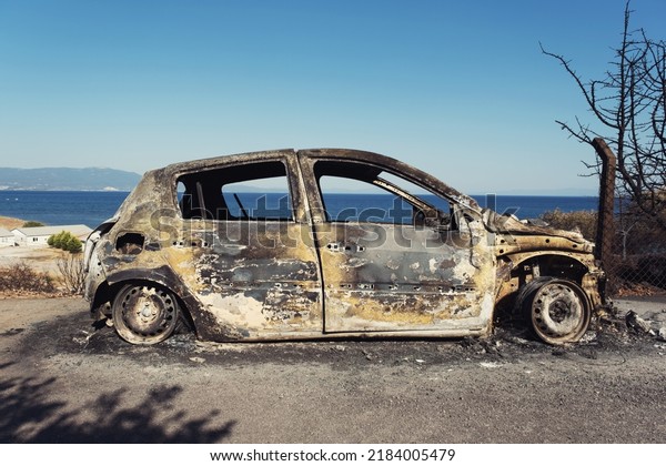Izmir, Turkey - July 23, 2022: Side view of a\
Burnt car aftermath the forest fire at Derya Site Seferihisar Izmir\
Turkey.