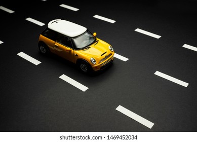 Izmir, Turkey - July 28, 2019: Top View Of A Mini Cooper S Yellow Toy Car On A Road With Road Lanes.