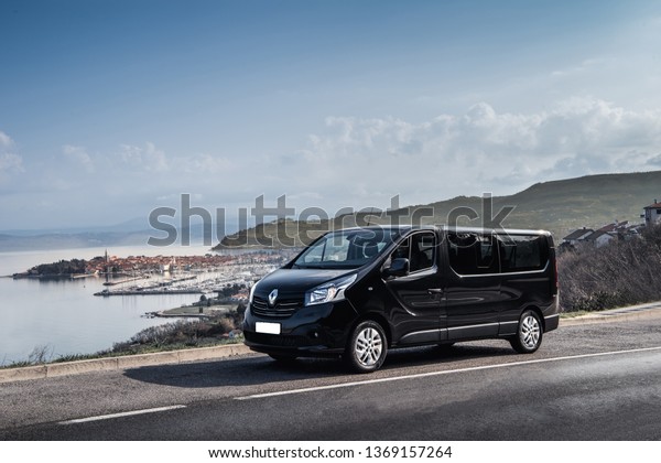 Izola, Slovenia-03.03.2019: Black\
Van for transport or delivery with mediterranean\
landscape